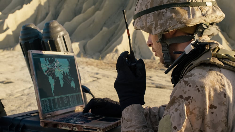 Soldier using a laptop and military radio for communication