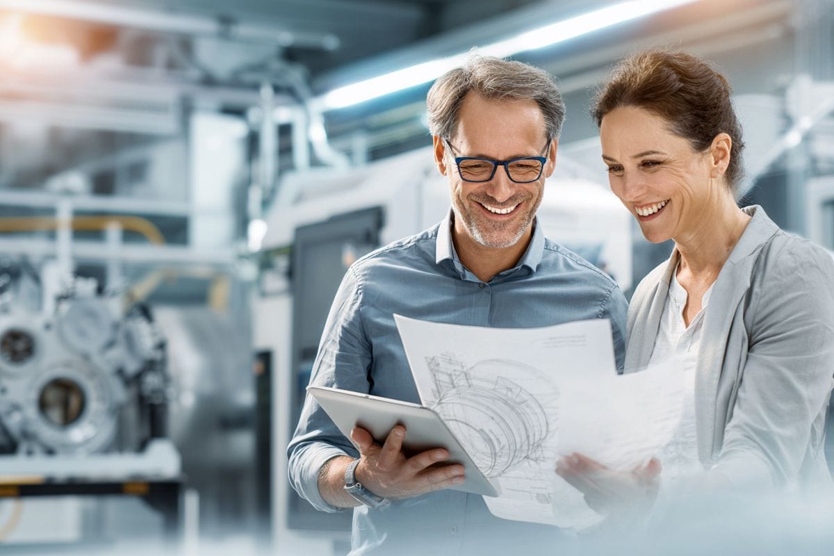 2 Personen stehen in der Fretigung und schauen sich technische Zeichnung an