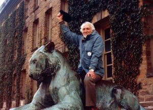 Democracy Incorporated: Sheldon Wolin waving his hat while riding the statue of a lioness in front of Princeton University's precincts.