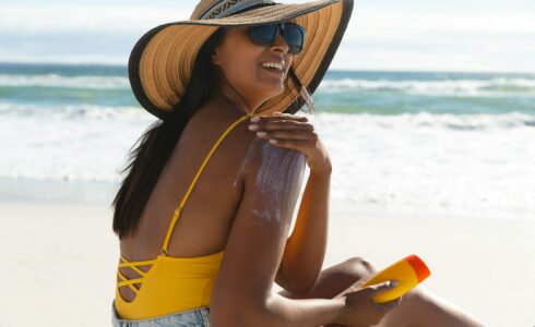 Smiling woman on beach using sunscreen to maximize vitamin D in Boise Idaho