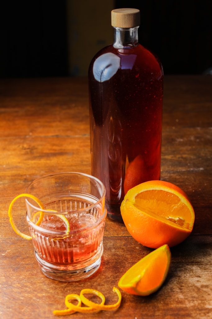 Une bouteille de Negroni accompagnée d'une tranche d'orange.
