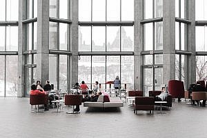 Consultancy recruitment - people sitting on armchairs and talking in a large room with large floor to ceiling windows