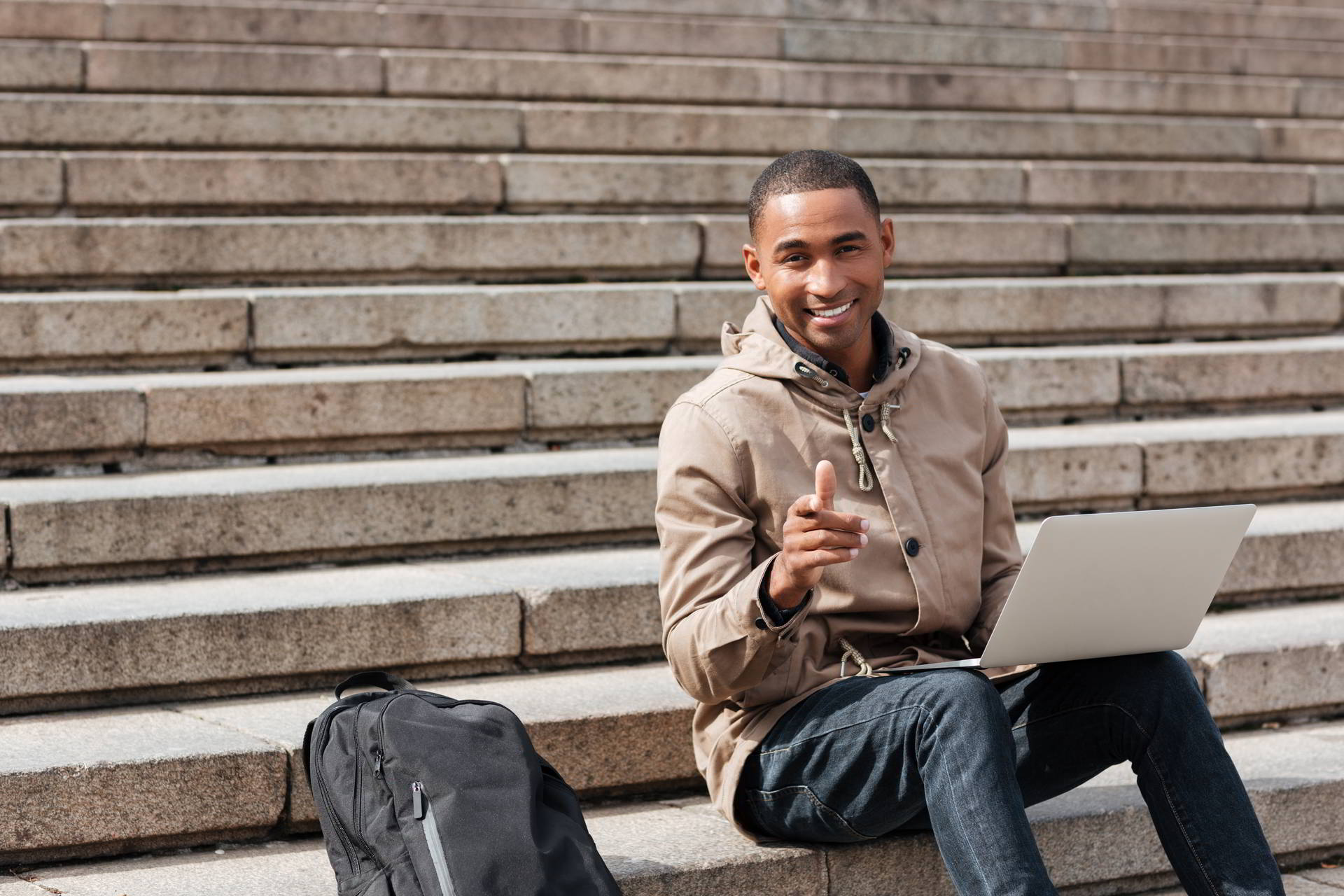 picture young african happy sitting staircase using laptop while pointin