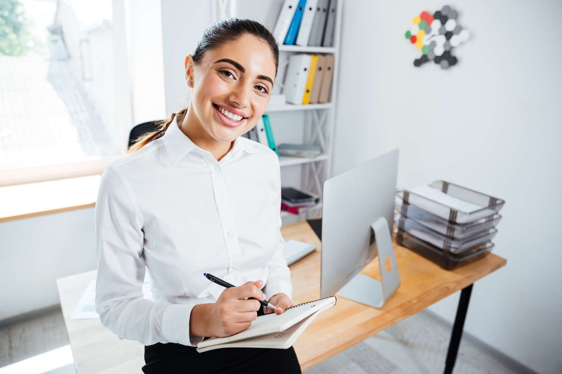 close portrait smiling happy businesswoman making notes while sitting offi