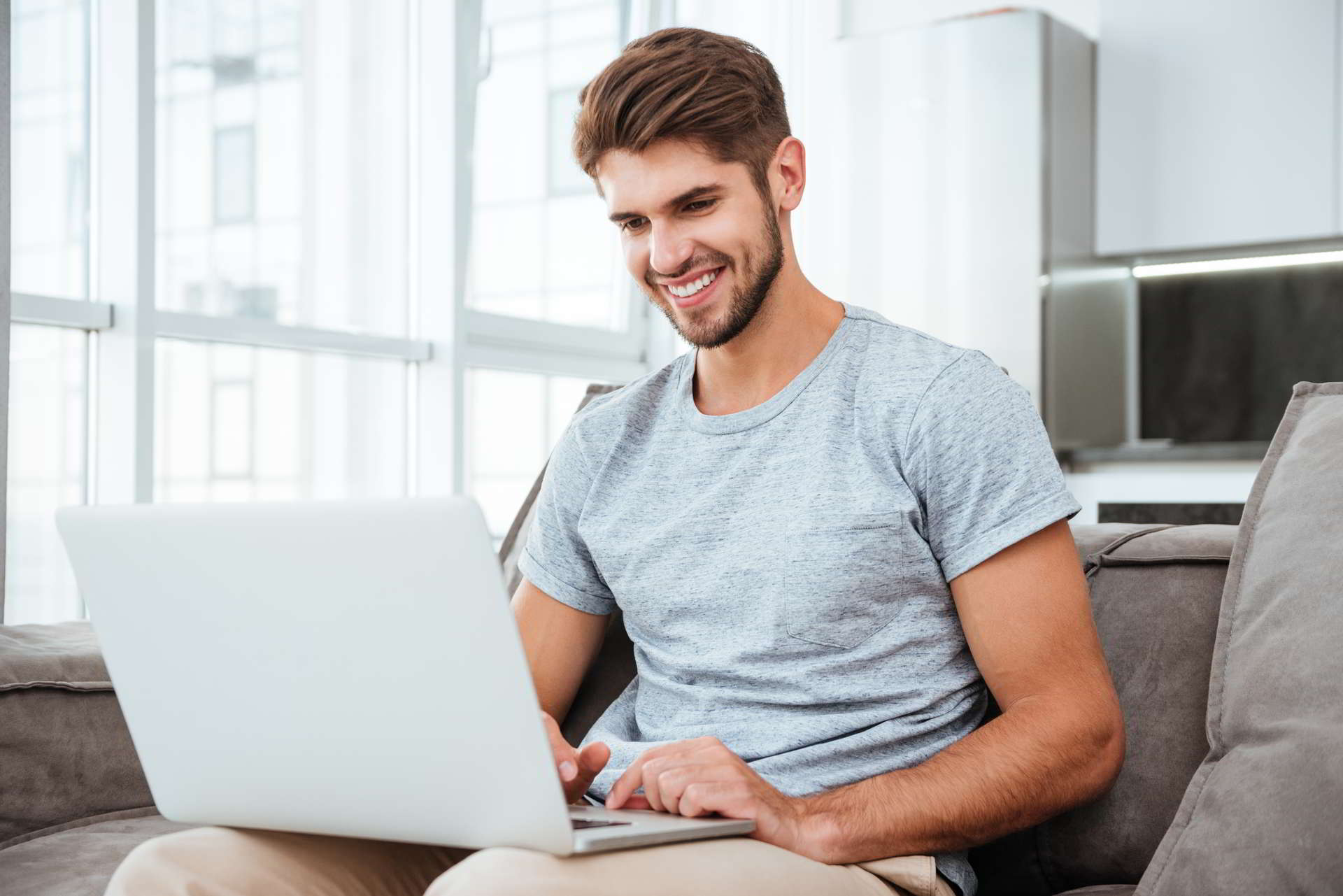 happy young shirt sitting sofa home working laptop computer smil