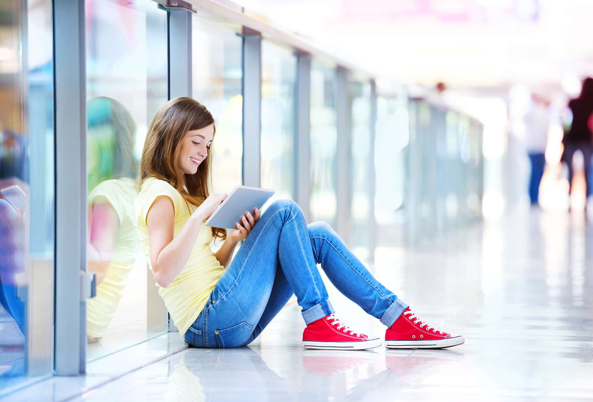 pretty young girl sitting floor shopping mall using tablet