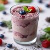 A-Delicious-And-Nutrient-Packed-Berry-Blast-Smoothie-featured-image-200x600w-reddish-pink-smoothies-glass-jars-several-types-of-berries-scattered-fresh-green-leaves-frosted-fusions