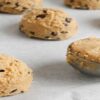 Easy-Homemade-Cookie-Dough-Ice-Cream-Recipe-update-dec24-featured-image-207x620w-cropped-blobs-of-cookie-dough-being-scooped-on-parchmant-paper-for-baking-frosted-fusions