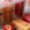 Fun-Easy-Homemade-Ice-Lollies-Popsicles-The-Perfect-Summer-Treat-featured image 637x1920 ice lollies lined up with some in mould and freesh fruit scattered Frosted-Fusions