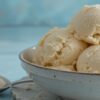 How-To-Fix-Icy-Homemade-Ice-Cream-And-Prevent-It-Next-Time-Featured-Image-close-up-of-smooth-creamy-vanilla-ice-cream-in-bowl-with-spoon-to-the-side-Frosted-Fusions