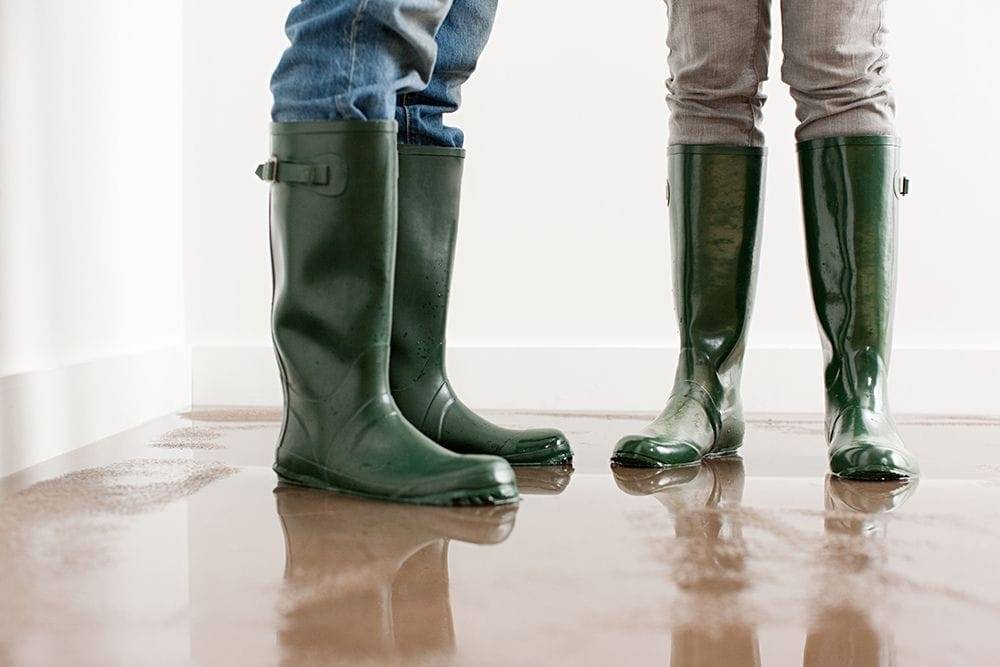 People stand in a puddle with rain boots. Why Is My Furnace Leaking Water?