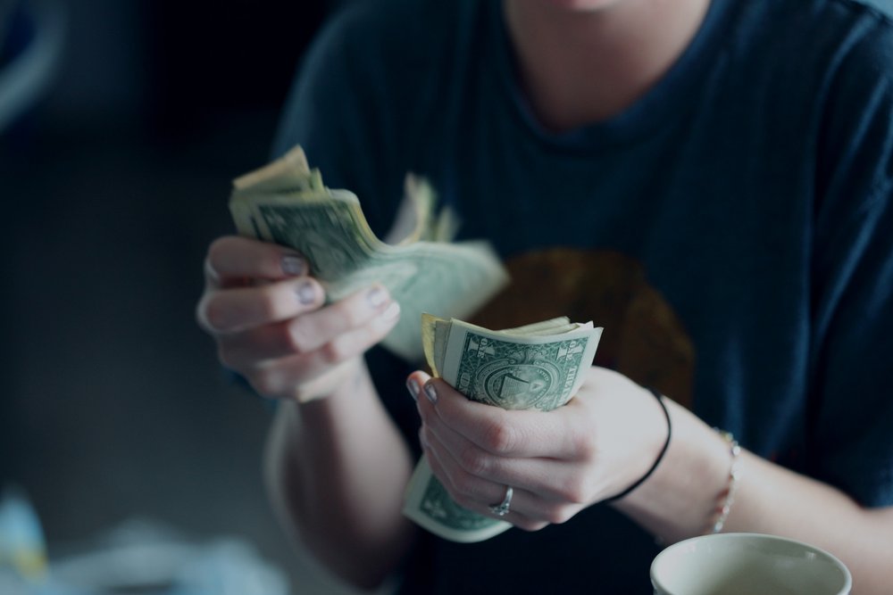 Uma mulher de vinte e quatro anos contando notas de dólar.
