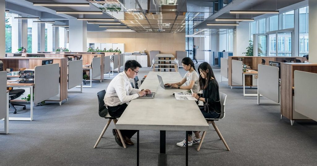 an open office workplace with communal desks and people at work
