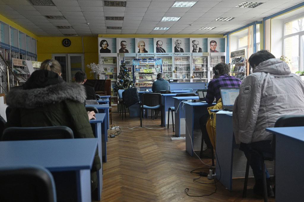 Des travailleurs profitent de la bibliothèque d'Irpin. (Photo by Genya SAVILOV / AFP)