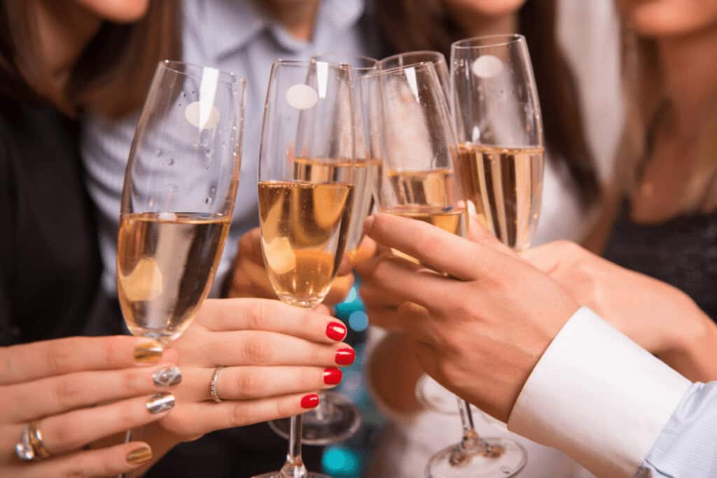 A group of people holding and clinking champagne glasses in a celebratory toast, embracing Polish New Year's traditions.