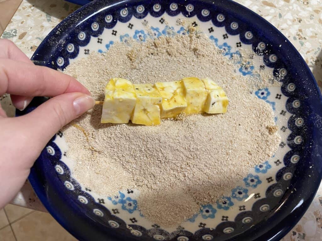 Gently coating cubes of marinated tofu in breadcrumbs, this delightful twist on a classic City Chicken recipe is artfully displayed on a decorative blue and white plate.