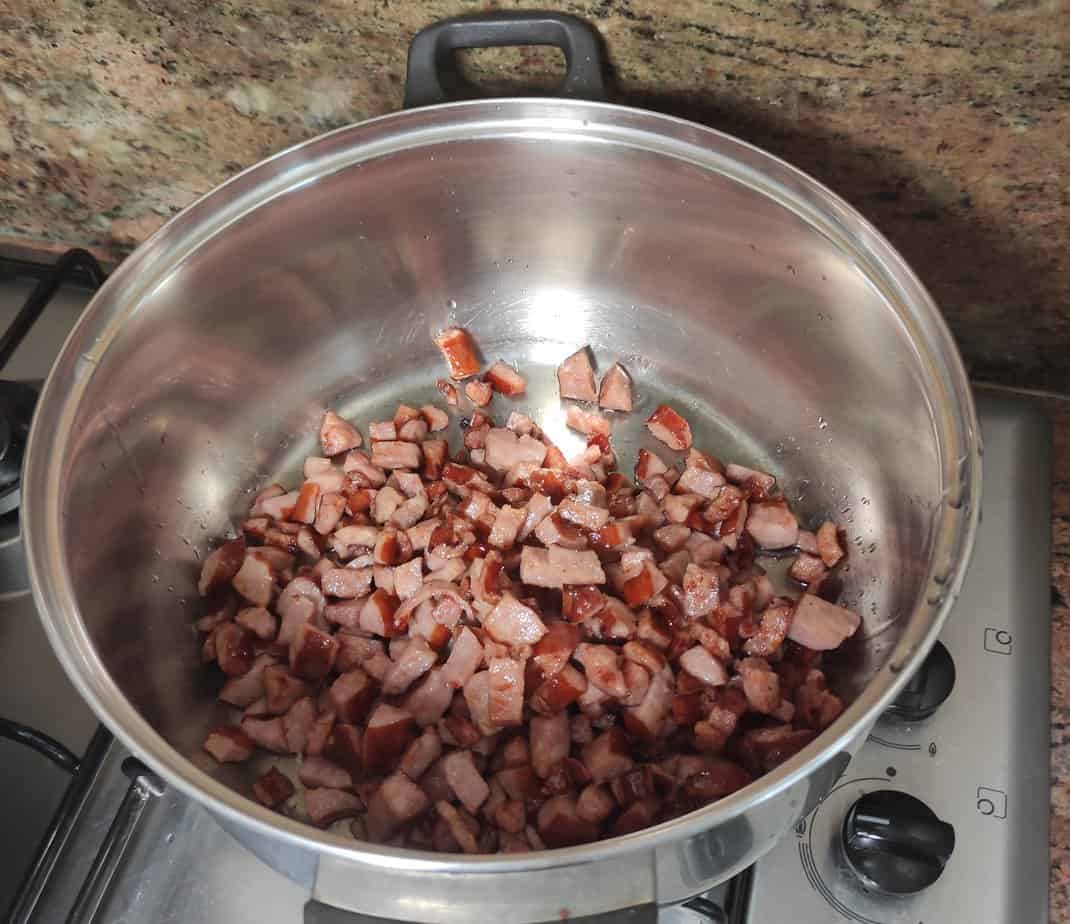 Diced sausage and chickpeas cooking in a stainless steel pot on a stove top for a delicious quick recipe.