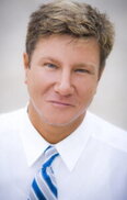 Professional headshot of a smiling man in a red polo shirt with light‑brown hair against a softly blurred background.