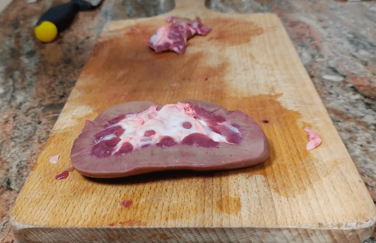 Pork kidneys on a chopping board.