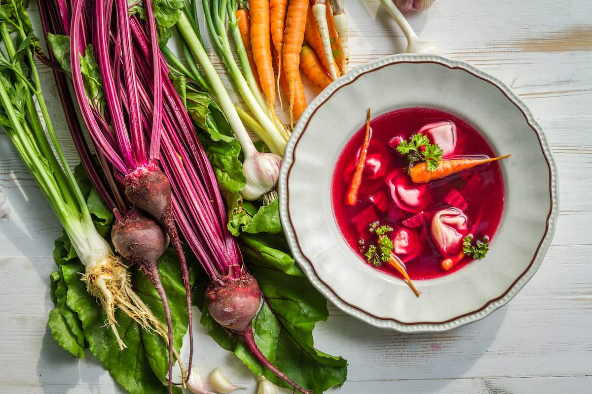 A bowl of Barszczyk soup with carrots and other vegetables.