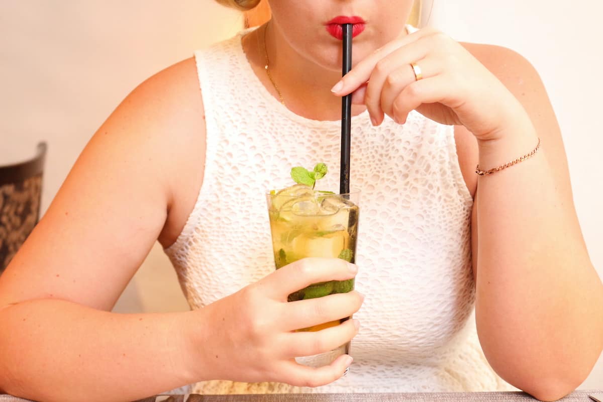 A woman savors a refreshing drink through a straw.