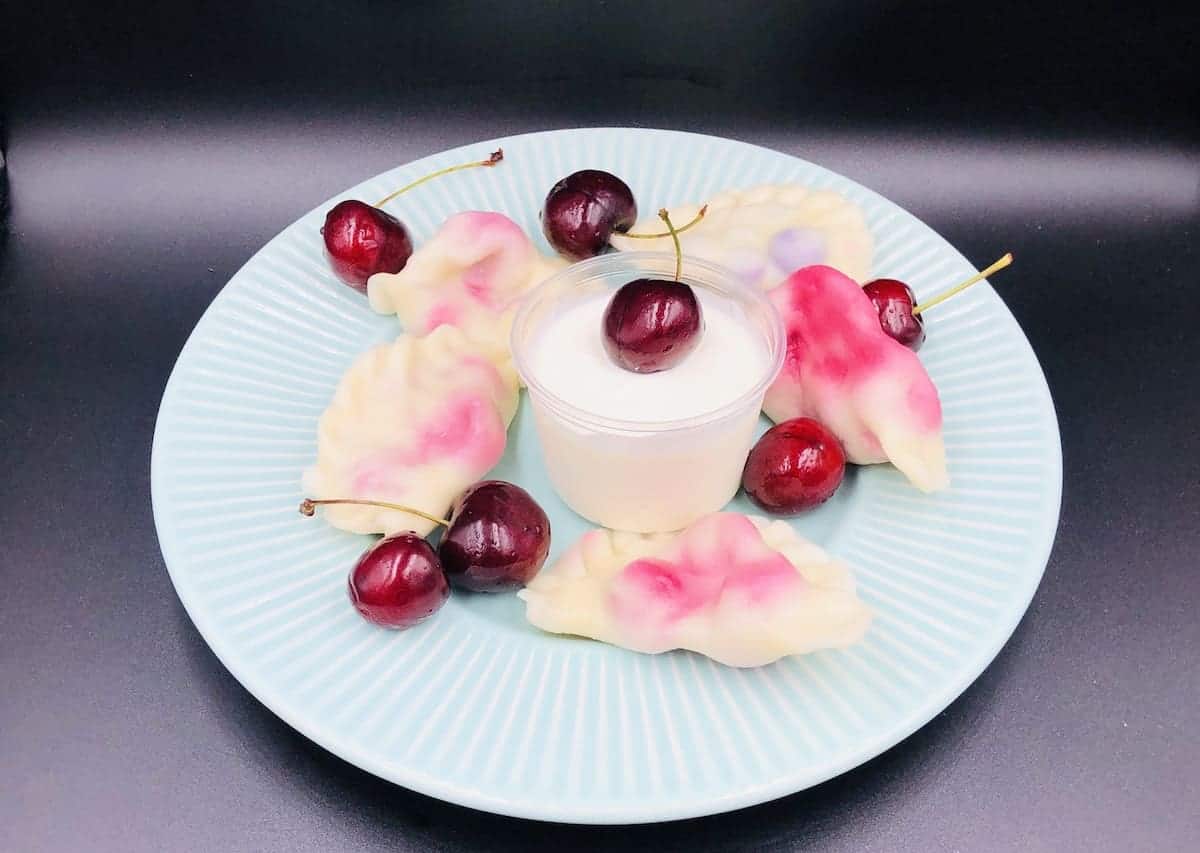 Homemade cherriy pierogi on a blue plate.