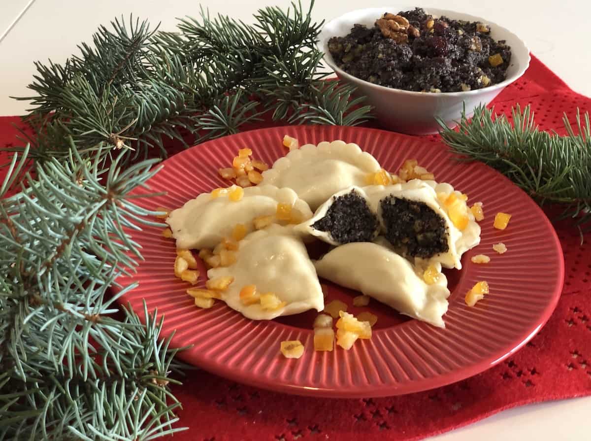 A plate with Polish Poppy Seed Pierogi and a bowl of fruit.