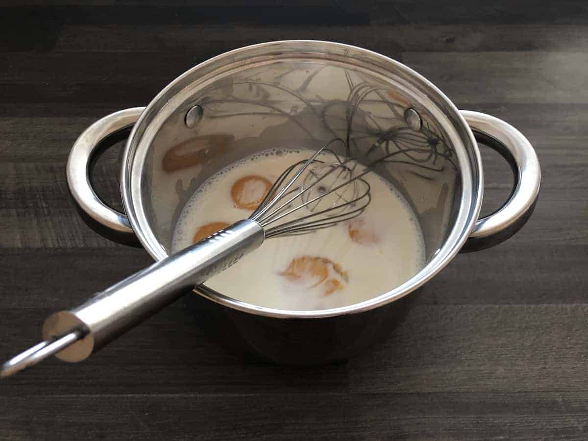 A traditional Polish dish featuring a pot of milk prepared with a whisk.