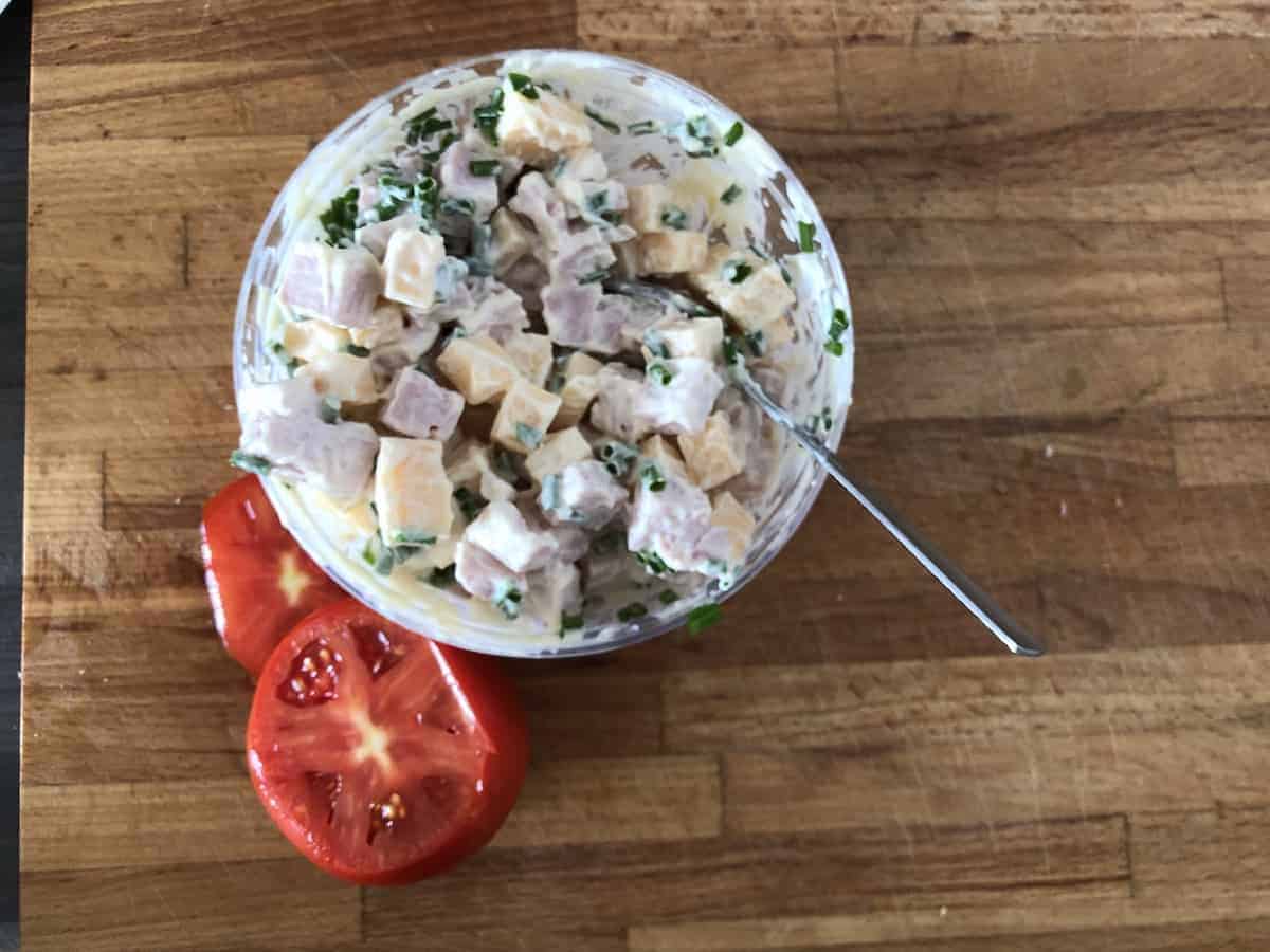 A Polish ham salad on a cutting board with stuffed tomatoes.