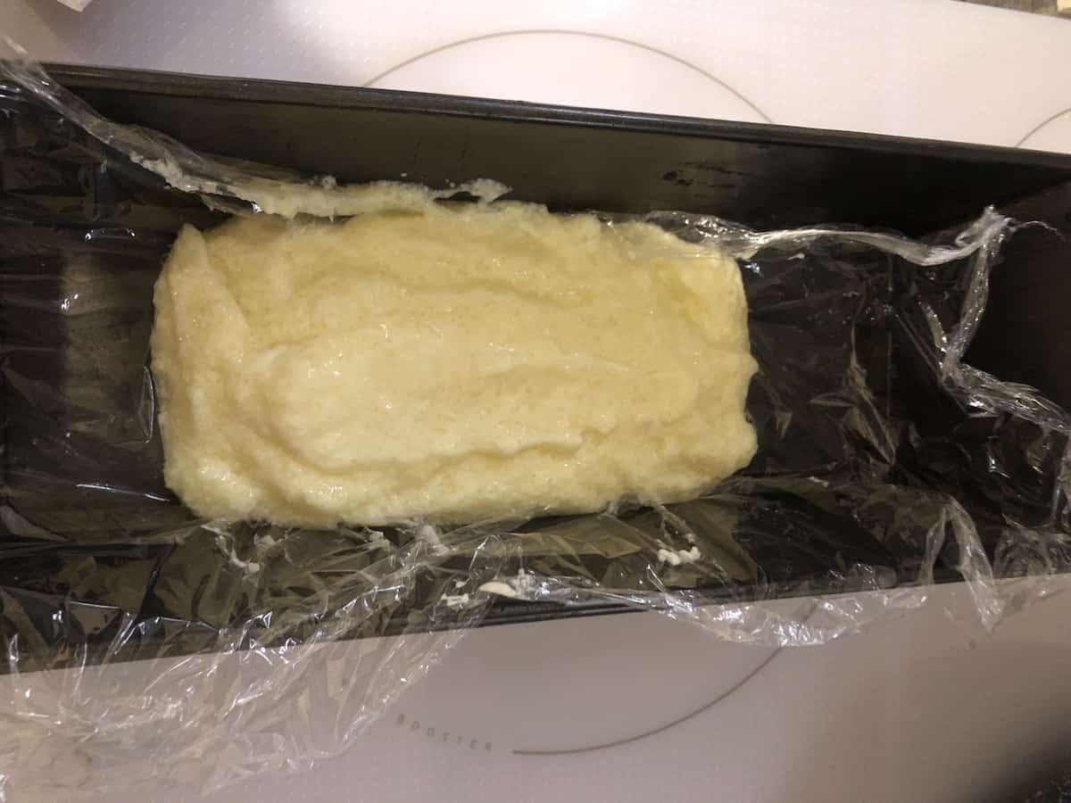 A homemade loaf of bread is sitting in a baking pan.