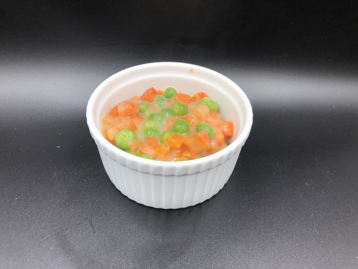 Creamed peas and carrots in a white bowl.