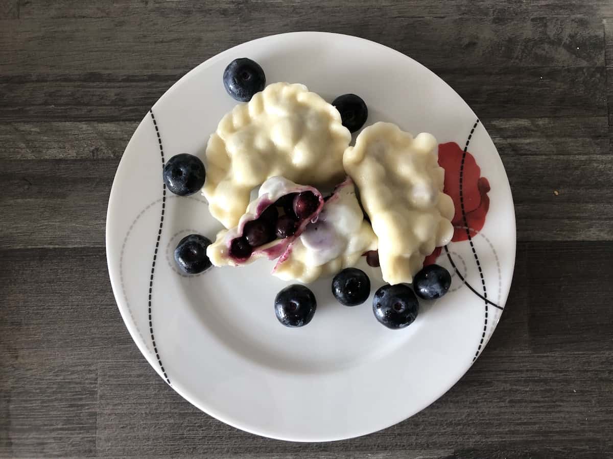 blueberry pierogi in a white plate.