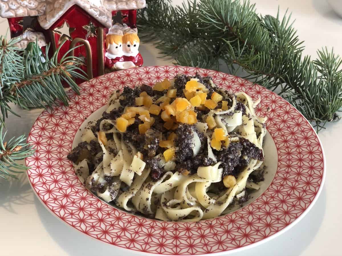 A plate of Polish Poppy Seed Noodles [Kluski Z Makiem] with fruit on top of a christmas tree.