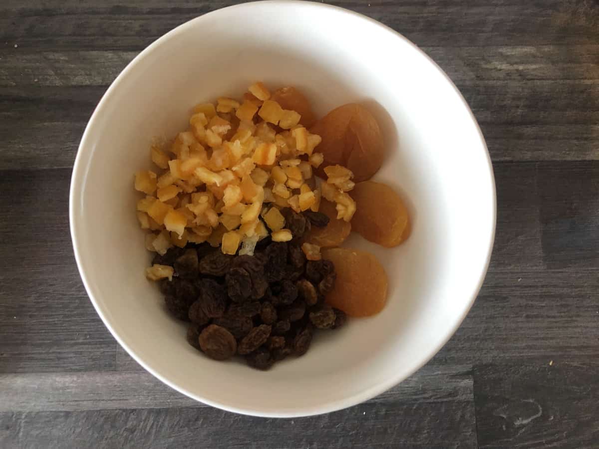Ground walnuts, apricots and cranberries in a white bowl.