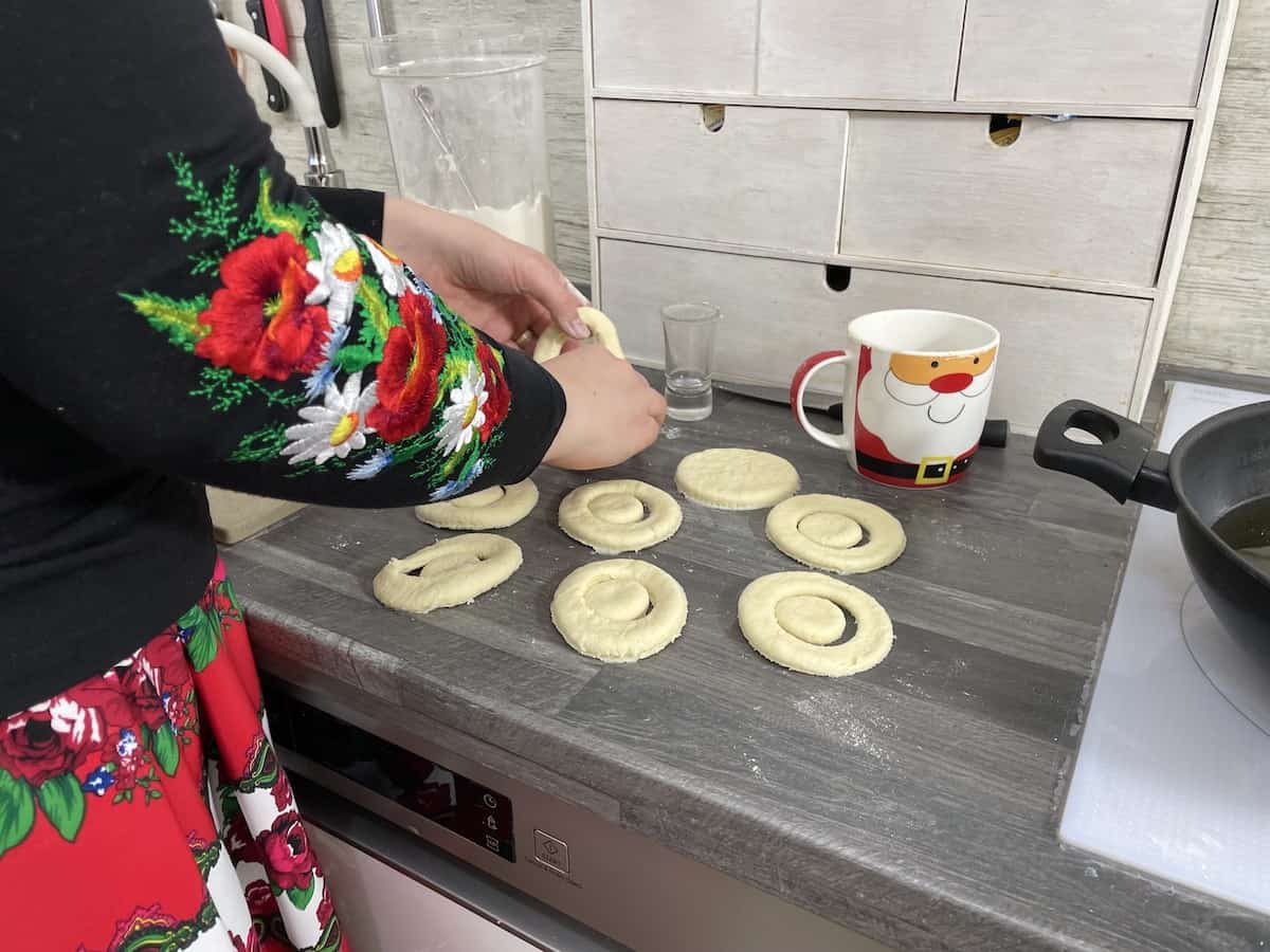 A woman is putting dough for Polish cheese donuts on a counter top.
