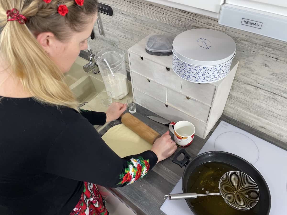 A woman is preparing Polish cheese donuts in a kitchen.