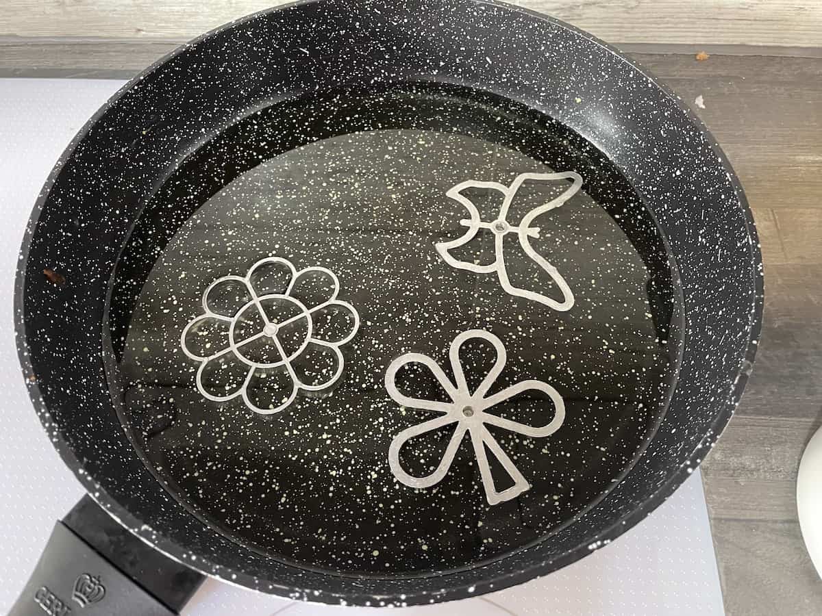 Heat the rosette shapes in the oil.