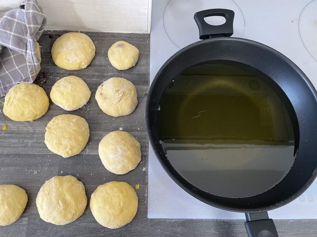 Donuts on a table next to heating oil.