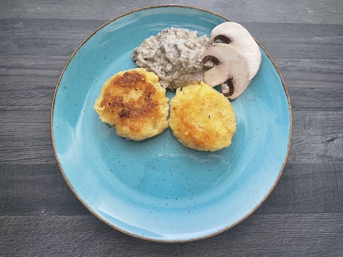Polish kotlety ziemniaczane with mushroom sauce in a blue plate.