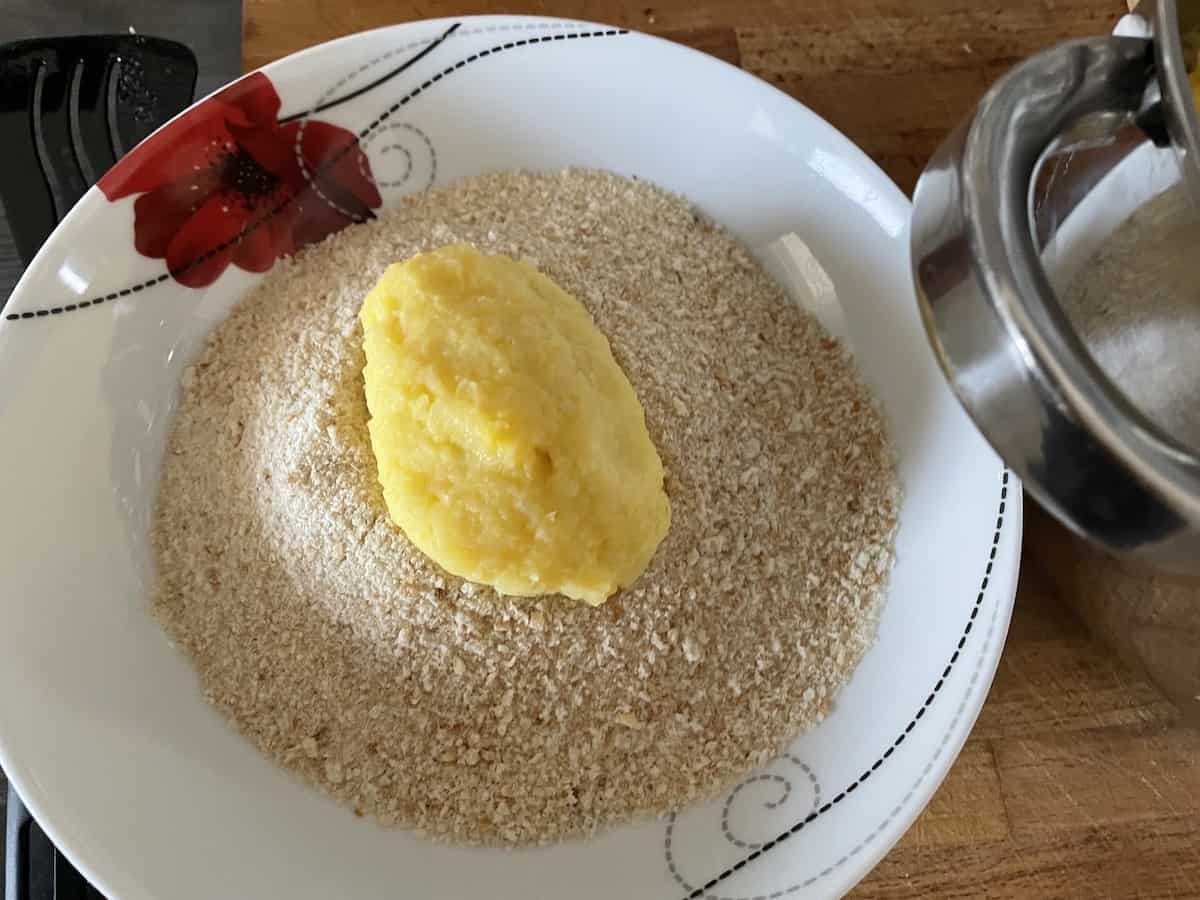 Coating the potato mash with breadcrumbs.