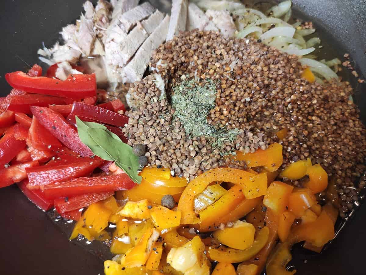 Buckwheat, chicken, veggies and spices in a skillet.