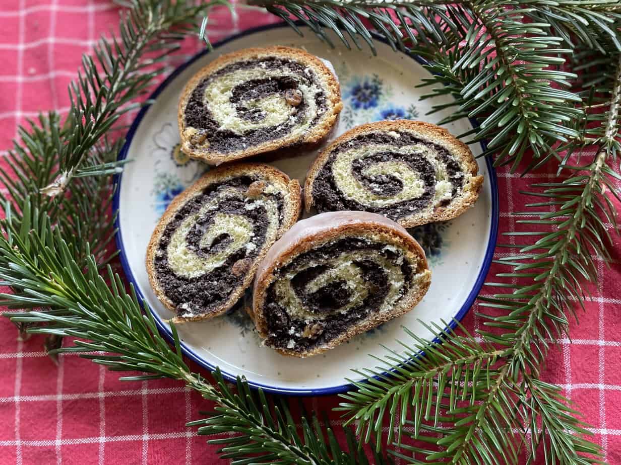 A poppyseed roll adorned with pine branches on a plate.
