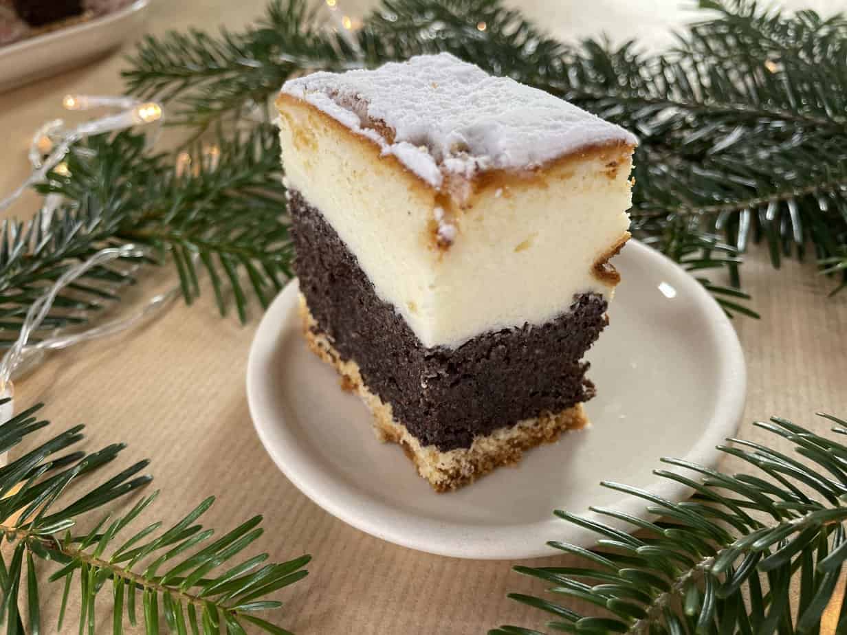 A slice of poppy seed cheesecake on a plate next to a Christmas tree.