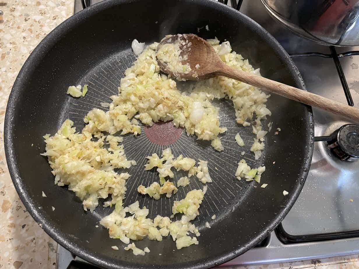 A frying pan with a wooden spoon on it, used for cooking Forszmak Lubelski, a Polish Meat Stew Recipe.