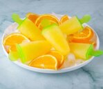 Fun-Easy-Homemade-Ice-Lollies-Popsicles-—-The-Perfect-Summer-Treat-image-6-plate-of-orange-citrus-ice-lollies-with-fresh-ornage-slices-Frosted-Fusions