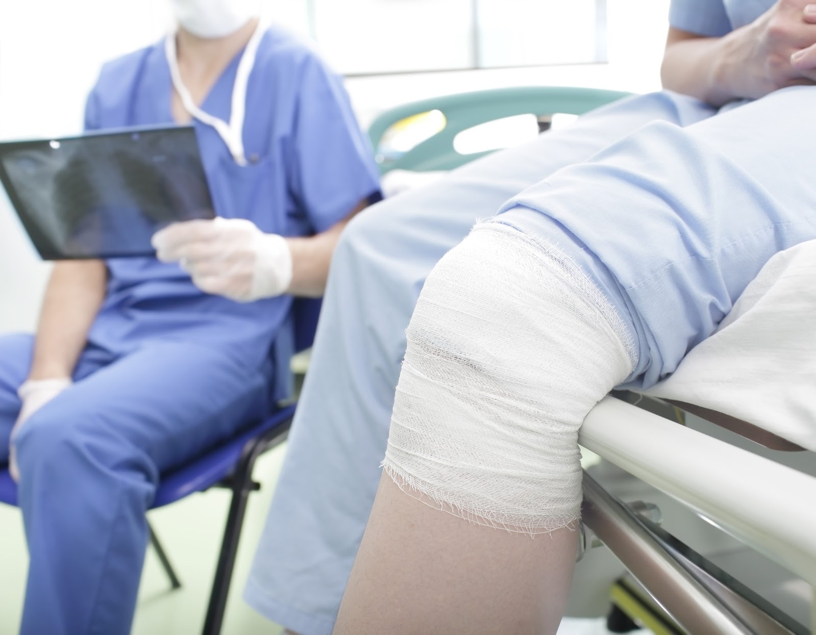 person with a bandaged knee sitting on a table in a doctors office, workers comp theme