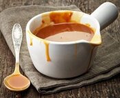how-to-pair-ice-cream-with-classic-christmas-desserts-image-3-white-pouring-jug-dilled-with-toffee-sauce-with-drips-down-the-side-and-spoon-covered-in-toffee-side-frosted-fusions