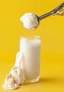 protein-shake-fusions-creating-protein-rich-low-fat-homemade-ice-cream-image-4-scoop-of-ice-cream-with-a-glass-of-milk-and-a-scoop-of-protein-powder-yellow-background-frosted-fusions