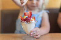 No-Leap-Just-A-Scoop-Ice-Cream-Flavours-To-Spring-Into-March-image-8-young-child-dipping-into-an-ice-cream-sundae-in-tall-glass-frosted-Fusions