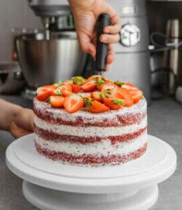 learn-how-to-make-homemade-ice-cream-cakes-image-9-woman-layering-an-ice-cream-cake-with-spatula-showing-layers-and-pile-of-fresh-strawberries-on-top-frosted-fusions